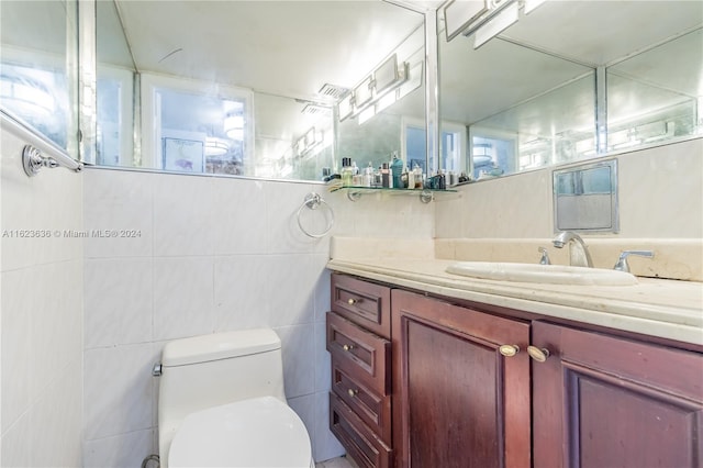 bathroom featuring vanity, tile walls, and toilet