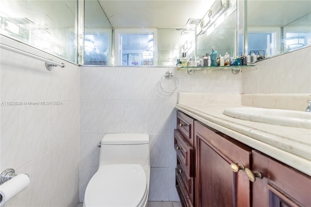 bathroom with vanity, tile walls, and toilet