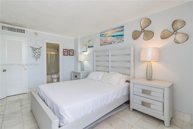 tiled bedroom featuring ensuite bathroom and a textured ceiling