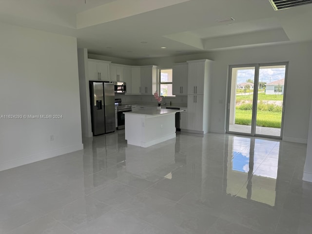 kitchen with white cabinets, a kitchen island, stainless steel appliances, and a healthy amount of sunlight