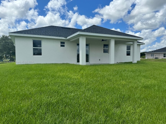 rear view of property featuring ceiling fan and a yard