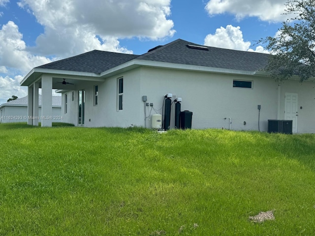 back of property featuring cooling unit, ceiling fan, and a lawn