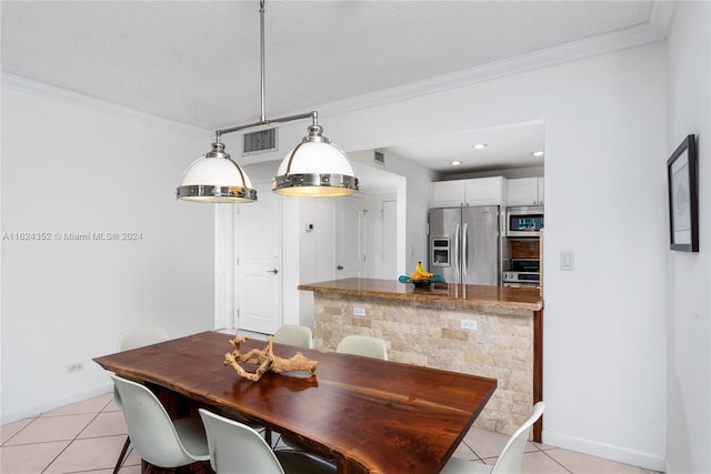 tiled dining room featuring a textured ceiling and ornamental molding