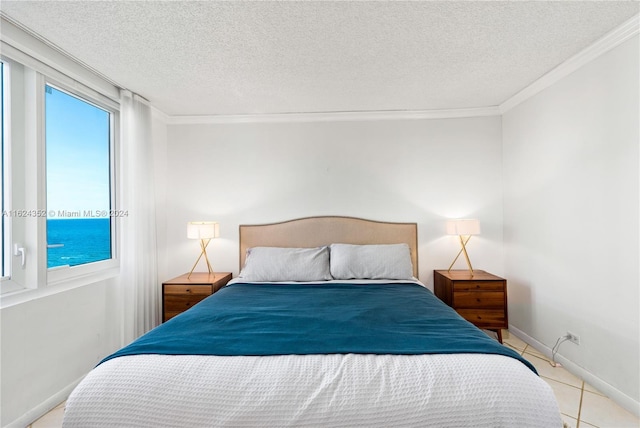 bedroom featuring a water view, ornamental molding, a textured ceiling, and light tile patterned floors