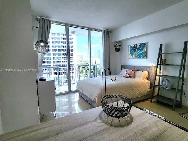 bedroom with access to exterior, a wall of windows, and a textured ceiling