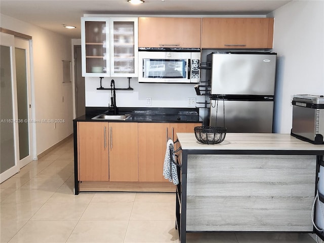 1750 N Bayshore Dr Unit 1204, Miami, FL 33132 - kitchen featuring stainless steel appliances, a sink, glass insert cabinets, light tile patterned floors, and dark countertops
