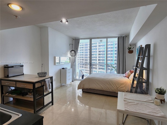 bedroom featuring expansive windows, light tile patterned floors, and a textured ceiling