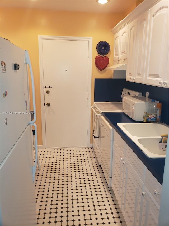 kitchen with sink, white cabinets, light tile patterned floors, and white appliances