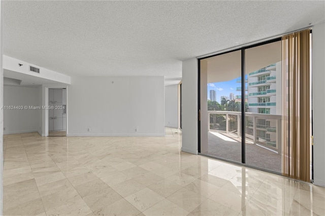 tiled spare room with floor to ceiling windows and a textured ceiling