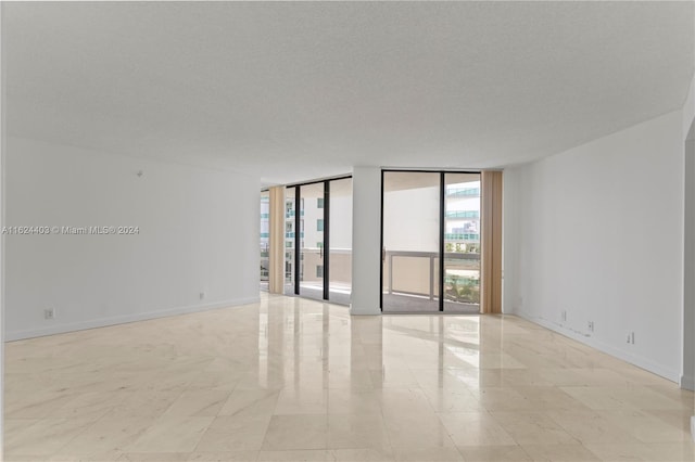 tiled empty room featuring a textured ceiling and expansive windows