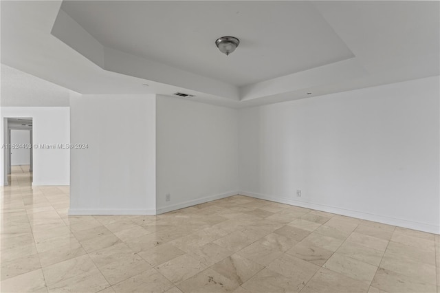 unfurnished room featuring light tile patterned flooring and a raised ceiling