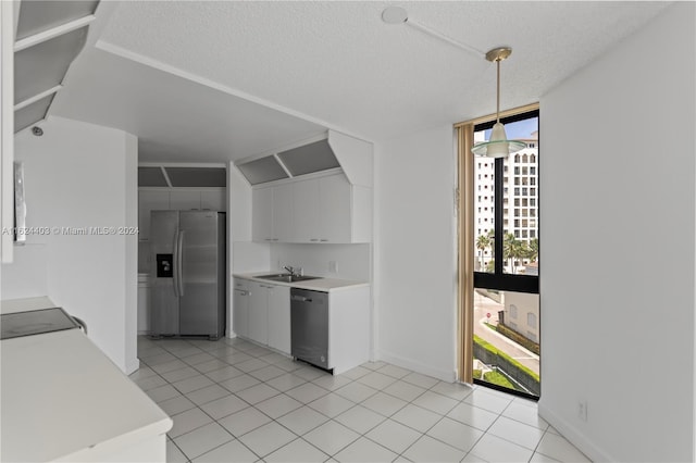 kitchen with light tile patterned floors, white cabinets, hanging light fixtures, appliances with stainless steel finishes, and sink