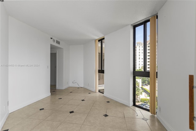 unfurnished room featuring a wall of windows and light tile patterned floors