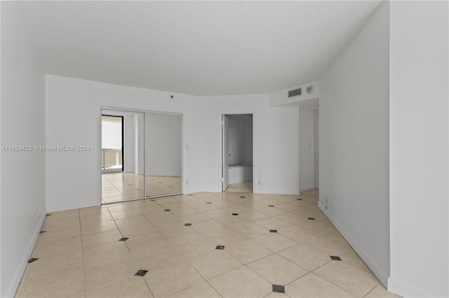 20185 E Country Club Dr Unit 502, Aventura, FL 33180 - unfurnished bedroom with a closet, visible vents, a textured ceiling, baseboards, and tile patterned flooring