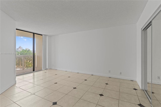 tiled spare room featuring a textured ceiling and floor to ceiling windows