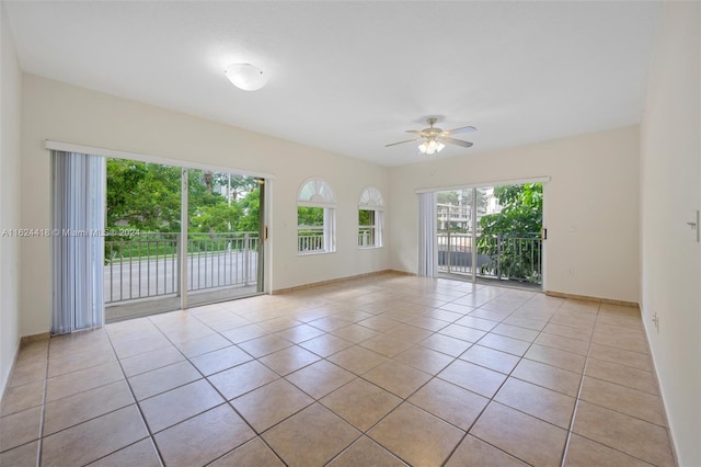 empty room featuring plenty of natural light, light tile patterned flooring, and ceiling fan