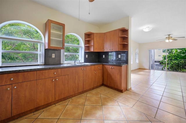 kitchen featuring dark stone counters, tasteful backsplash, sink, ceiling fan, and light tile patterned flooring