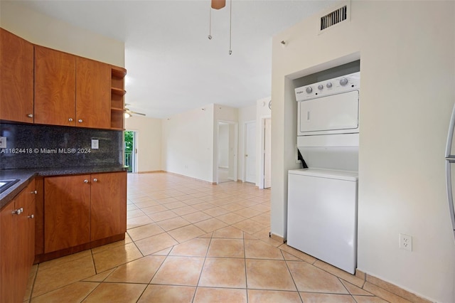 kitchen with backsplash, ceiling fan, stacked washer / drying machine, and light tile patterned flooring