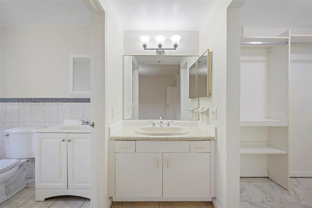 bathroom featuring toilet, tile patterned floors, vanity, a textured ceiling, and backsplash