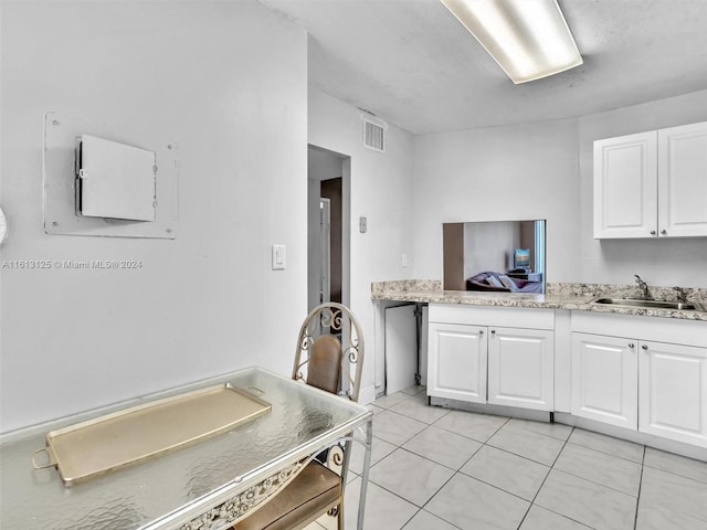 kitchen with white cabinetry, sink, and light tile patterned flooring