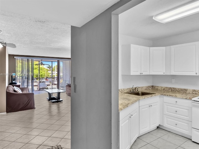 kitchen with white cabinetry, ceiling fan, light tile patterned flooring, and sink