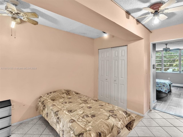 tiled bedroom with a textured ceiling, ceiling fan, and a closet