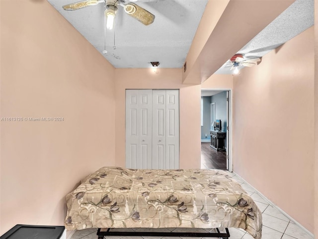 tiled bedroom with ceiling fan, a closet, and a textured ceiling