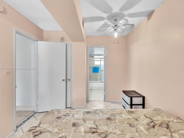 unfurnished bedroom with connected bathroom, light tile patterned floors, a closet, and a textured ceiling