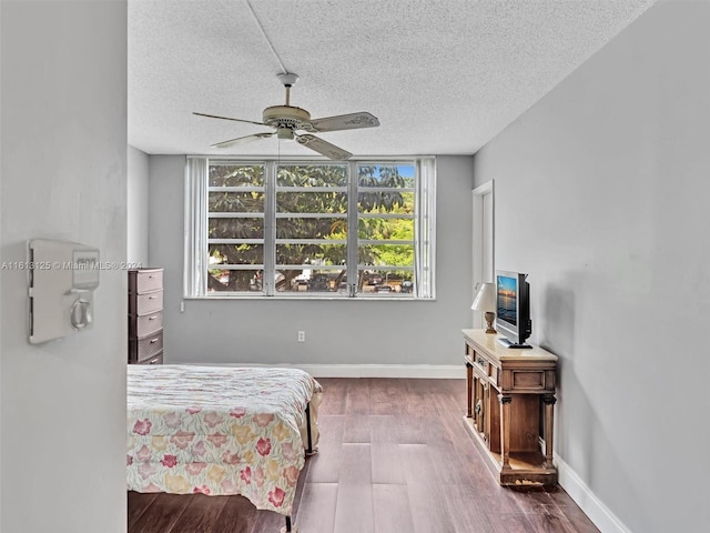 bedroom with ceiling fan, dark wood-type flooring, and a textured ceiling