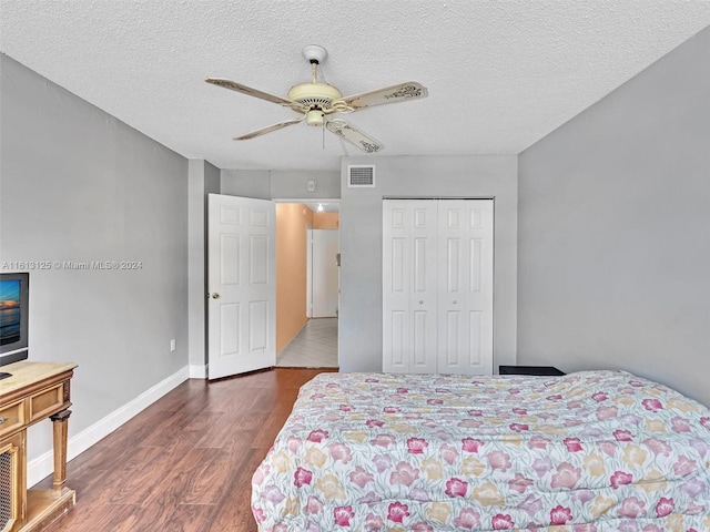 bedroom featuring ceiling fan, a closet, dark hardwood / wood-style floors, and a textured ceiling