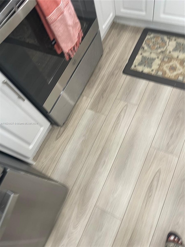 interior details with white cabinetry, light hardwood / wood-style flooring, and stove