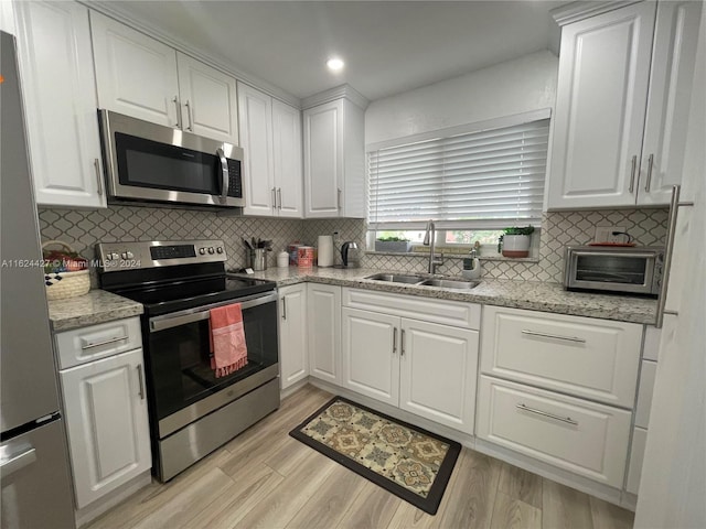 kitchen featuring white cabinets, tasteful backsplash, appliances with stainless steel finishes, and sink