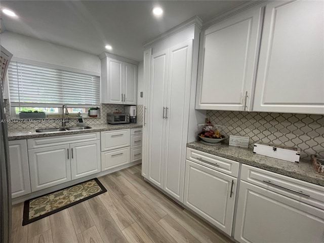 kitchen with stone counters, tasteful backsplash, sink, light hardwood / wood-style floors, and white cabinetry