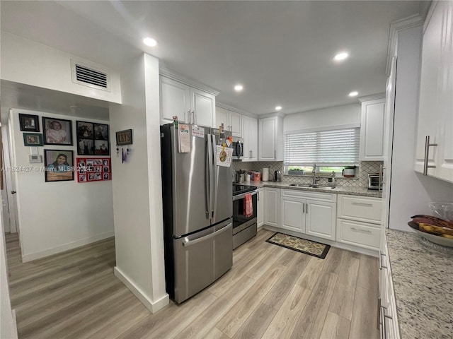 kitchen featuring white cabinetry, stainless steel appliances, decorative backsplash, light wood-type flooring, and sink