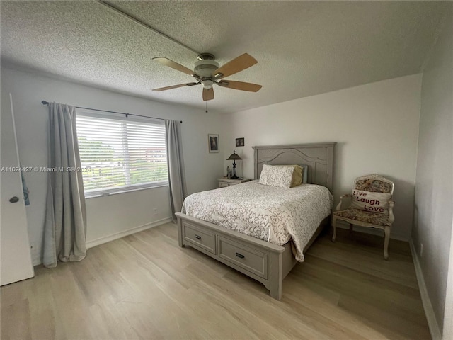 bedroom featuring a textured ceiling, light wood-type flooring, and ceiling fan