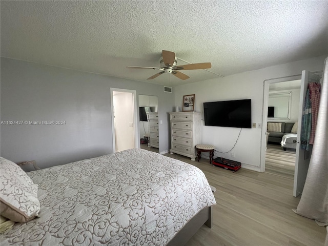 bedroom featuring light hardwood / wood-style flooring, a textured ceiling, and ceiling fan