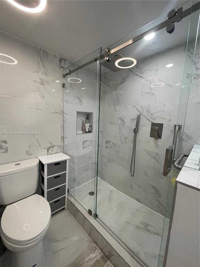 bathroom with tile patterned flooring, an enclosed shower, toilet, vanity, and tile walls