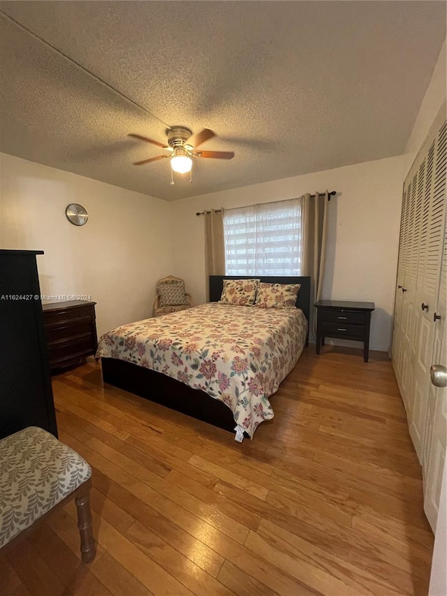 bedroom with ceiling fan, a textured ceiling, a closet, and hardwood / wood-style floors