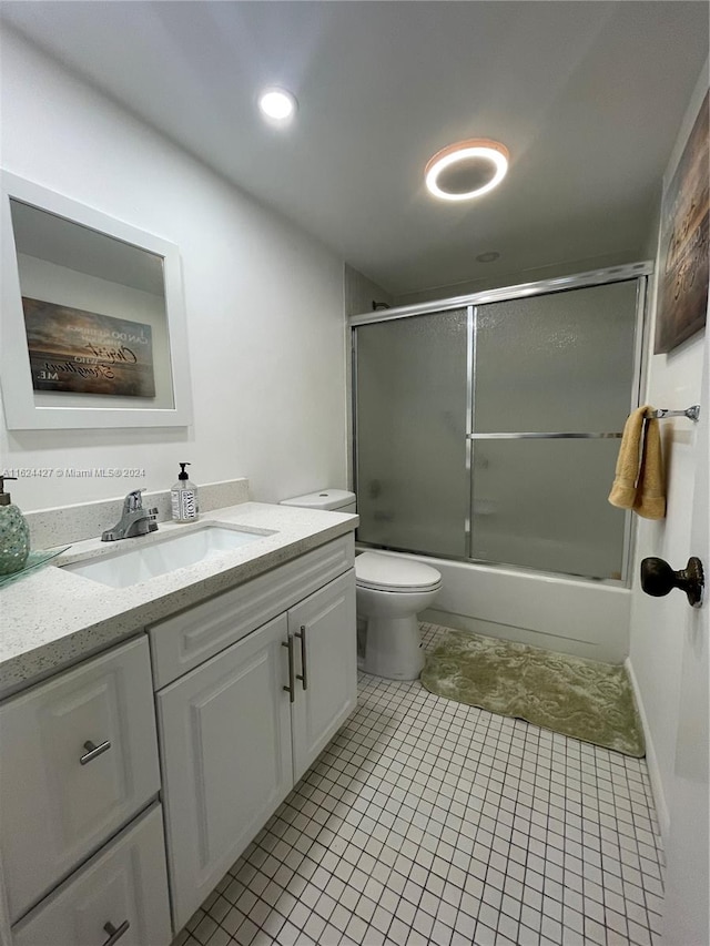 full bathroom featuring vanity, tile patterned floors, combined bath / shower with glass door, and toilet