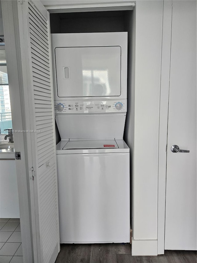 clothes washing area with sink, stacked washer / dryer, and dark hardwood / wood-style flooring