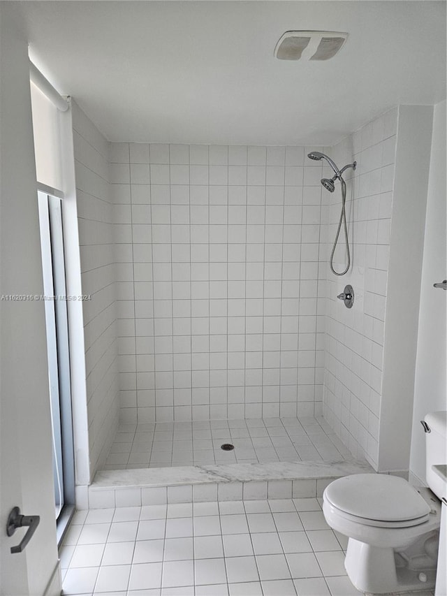 bathroom featuring tile patterned flooring, tiled shower, vanity, and toilet