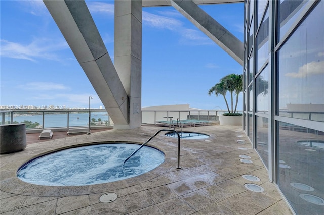 view of swimming pool featuring a water view, a patio area, and a community hot tub