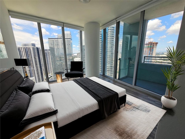 bedroom featuring access to exterior, a wall of windows, dark hardwood / wood-style flooring, and a water view