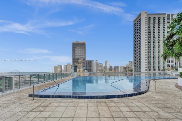 view of pool with a water view, a patio area, and a community hot tub