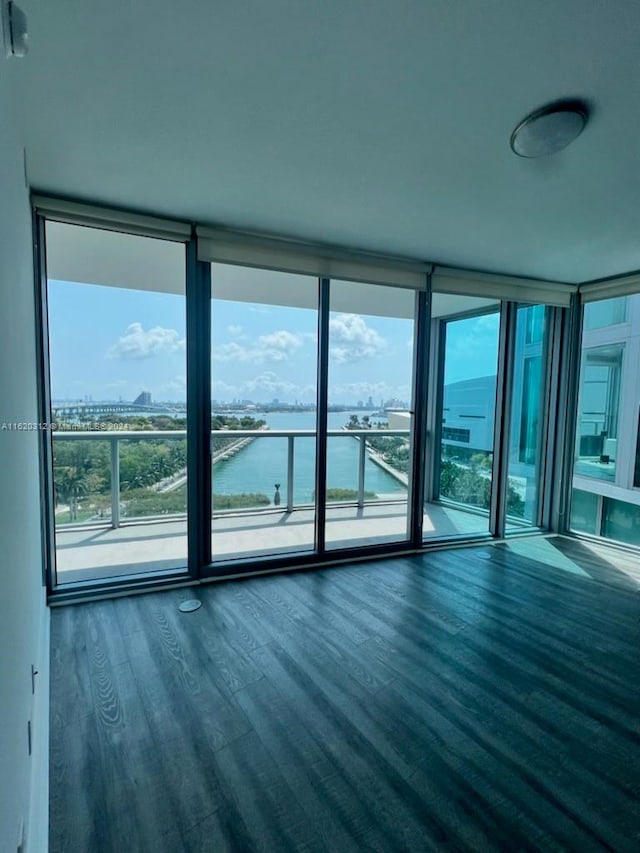 empty room featuring a water view, dark hardwood / wood-style floors, and expansive windows