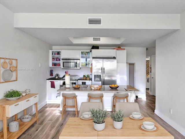 kitchen featuring appliances with stainless steel finishes, a kitchen breakfast bar, white cabinets, a kitchen island, and hardwood / wood-style floors