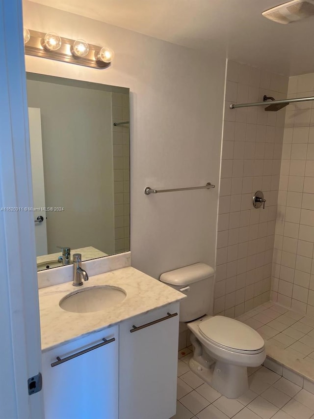 bathroom with a tile shower, vanity, toilet, and tile patterned floors