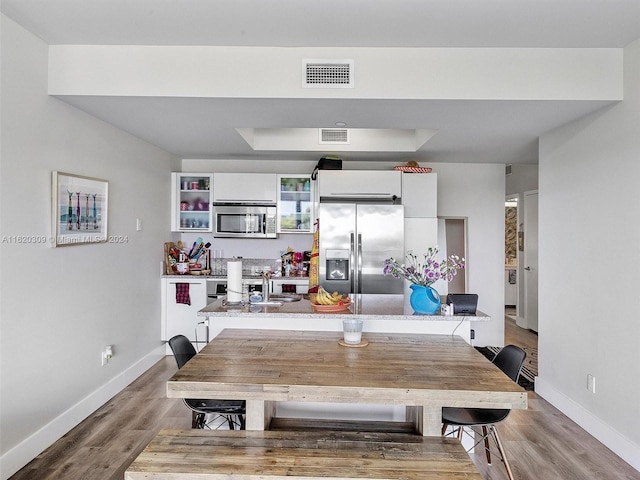 dining area featuring a tray ceiling and hardwood / wood-style flooring