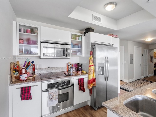 kitchen featuring sink, white cabinetry, stainless steel appliances, light stone counters, and dark hardwood / wood-style flooring