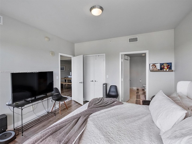 bedroom featuring hardwood / wood-style floors, ensuite bath, and a closet